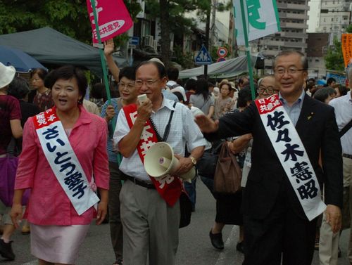 覚王山日泰寺の縁日で参拝客に後期高齢者医療制度廃止を訴えるさいとう愛子さん（左)と佐々木憲昭衆院議員（右)